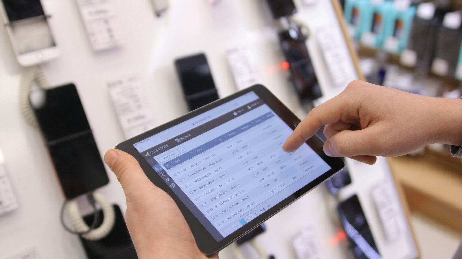 Hands holding a tablet showing a stock list in a shop