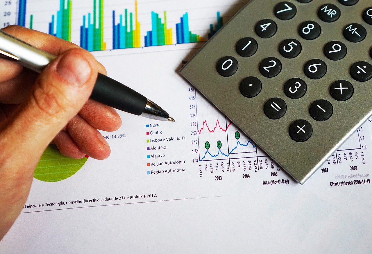 Pen and calculator resting on a printed business report with financial charts
