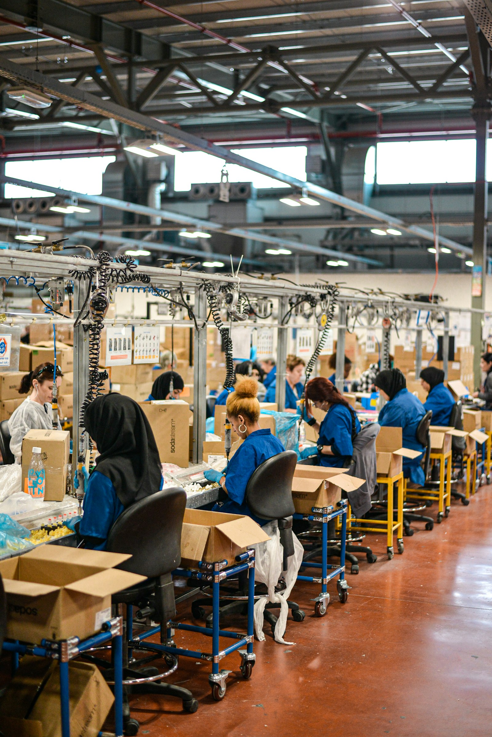 Operators in blue uniforms working at an assembly line in a large factory