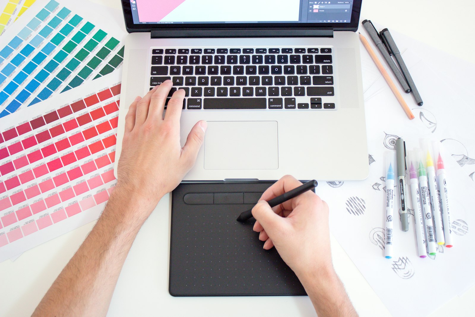 Designer working on a laptop beside colour swatches and markers