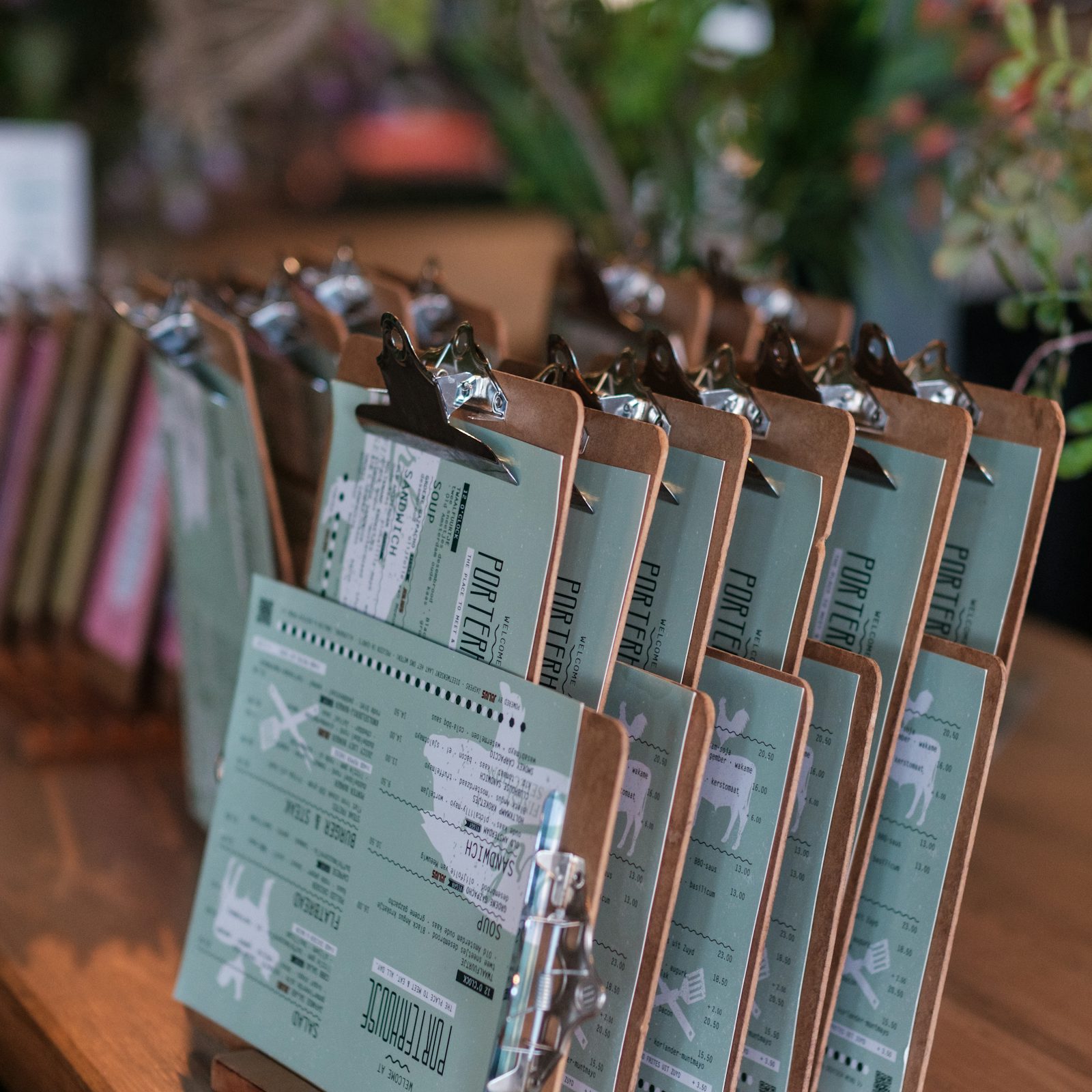 Several clipboards holding printed paper forms laid out on a wooden table