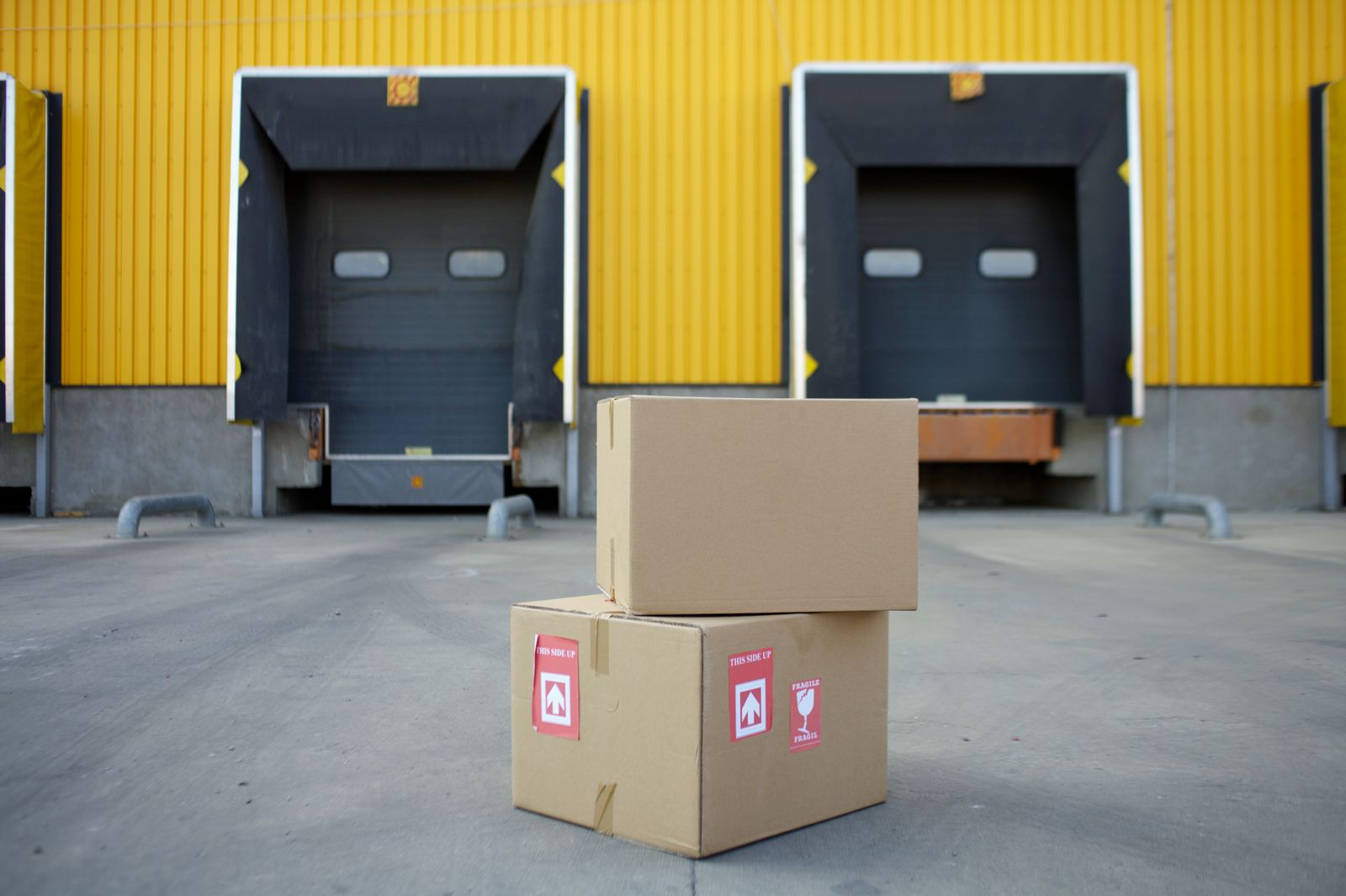 Cardboard boxes stacked in front of warehouse loading docks with yellow walls