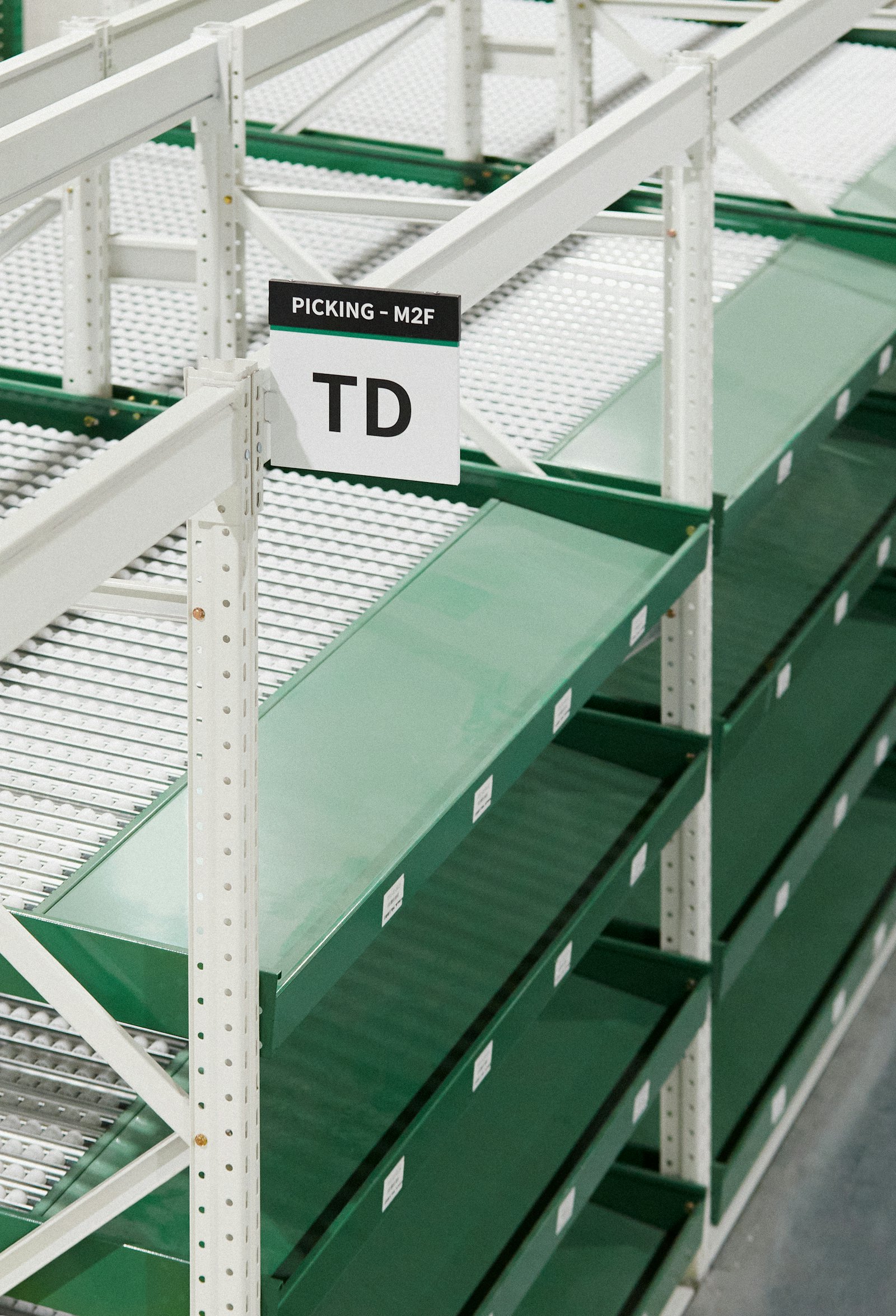 Empty green warehouse shelving with location signs, ready for stock to be slotted