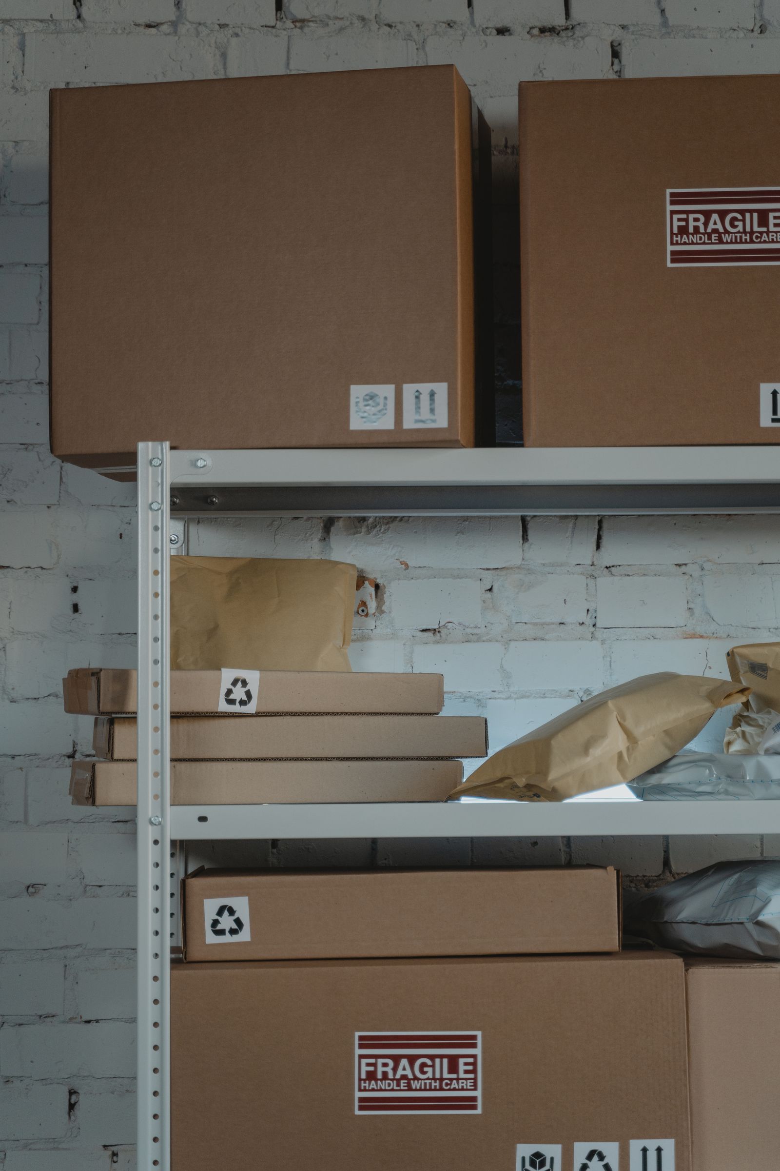 Brown cardboard boxes with fragile labels stacked on steel warehouse shelving
