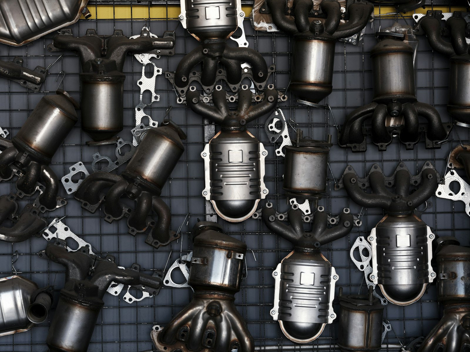 Used car exhaust systems and replacement parts hanging on a garage wall