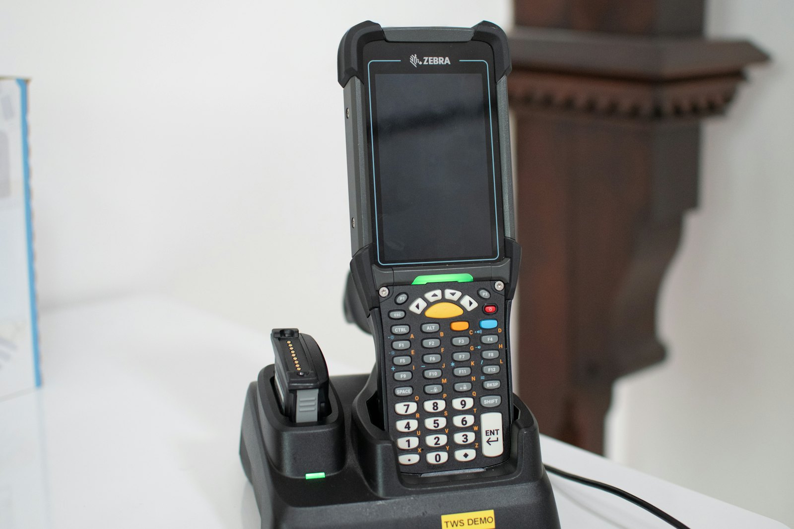 Handheld barcode scanner resting in its charging dock on a table