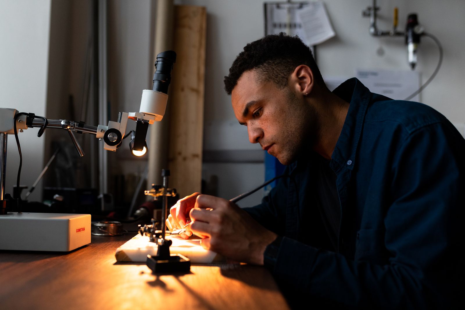 Engineer working with precision tools on electronic components in a workshop
