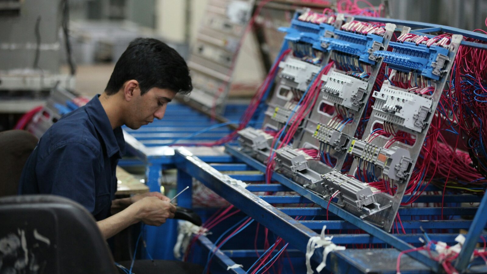 Technician assembling electrical equipment at a manufacturing workstation