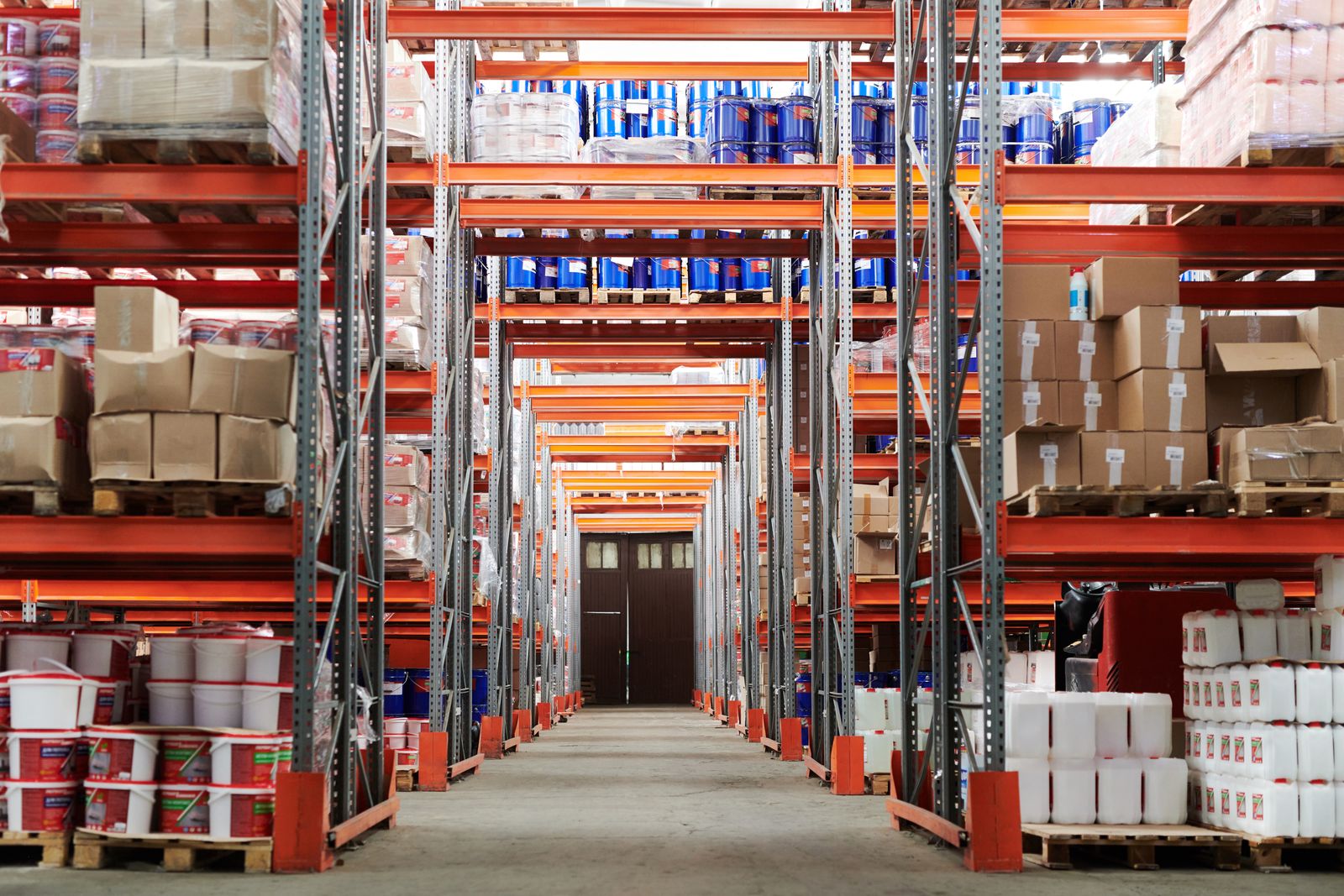 Wide view of a warehouse with stocked shelves and cardboard boxes on a concrete floor
