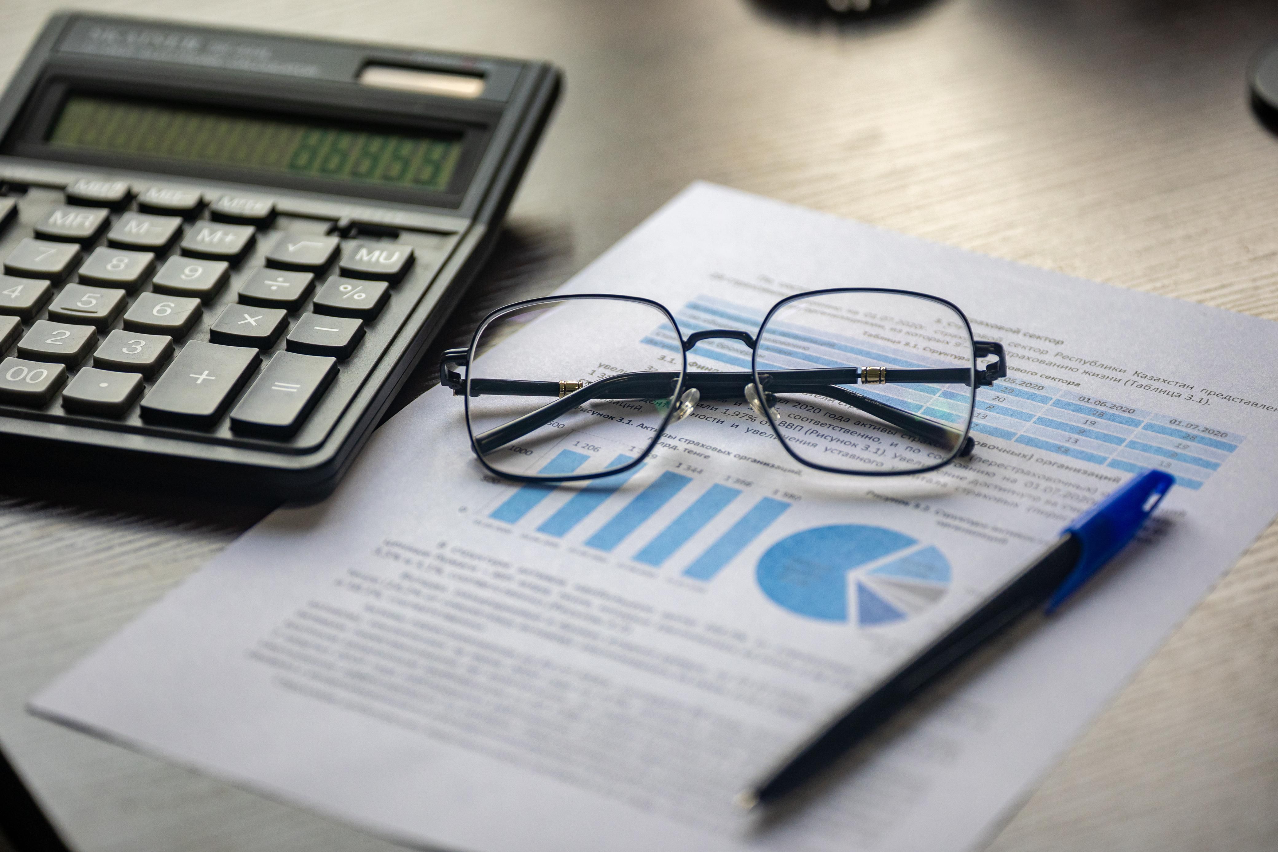 Financial document with a calculator, pen and glasses on a desk