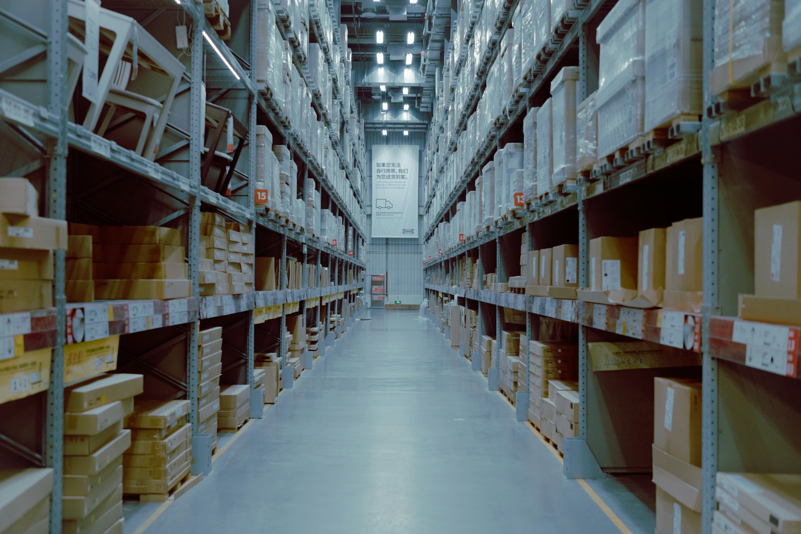 Long warehouse aisle lined with tall shelving under bright lighting
