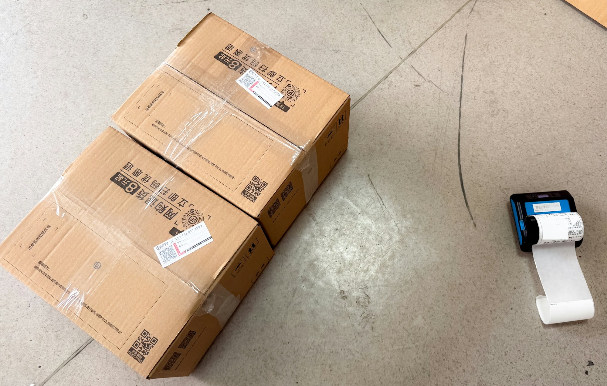 Cardboard parcels waiting to be scanned beside a small portable label printer