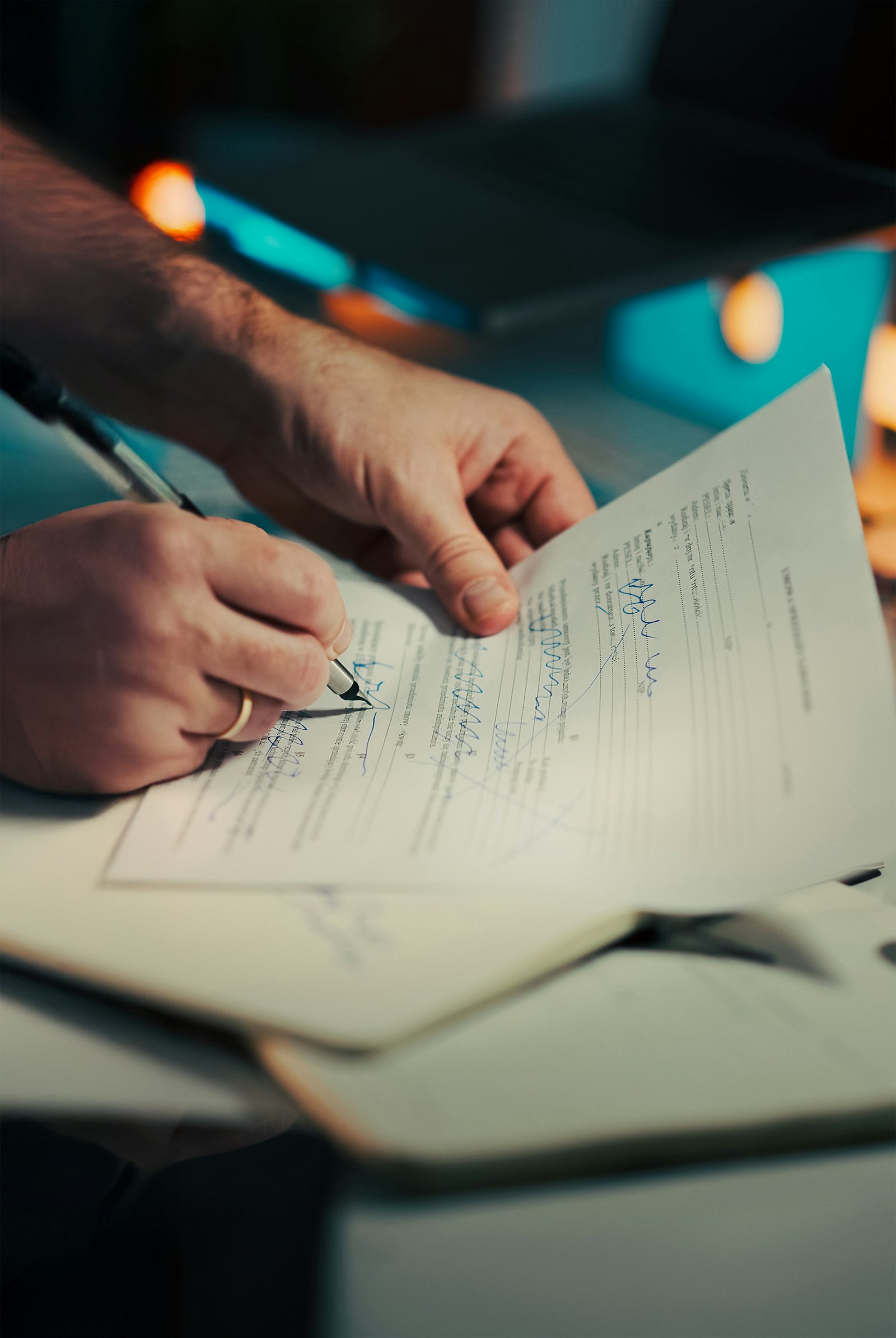 Close-up of a man's hands filling in and signing a printed agreement with a pen