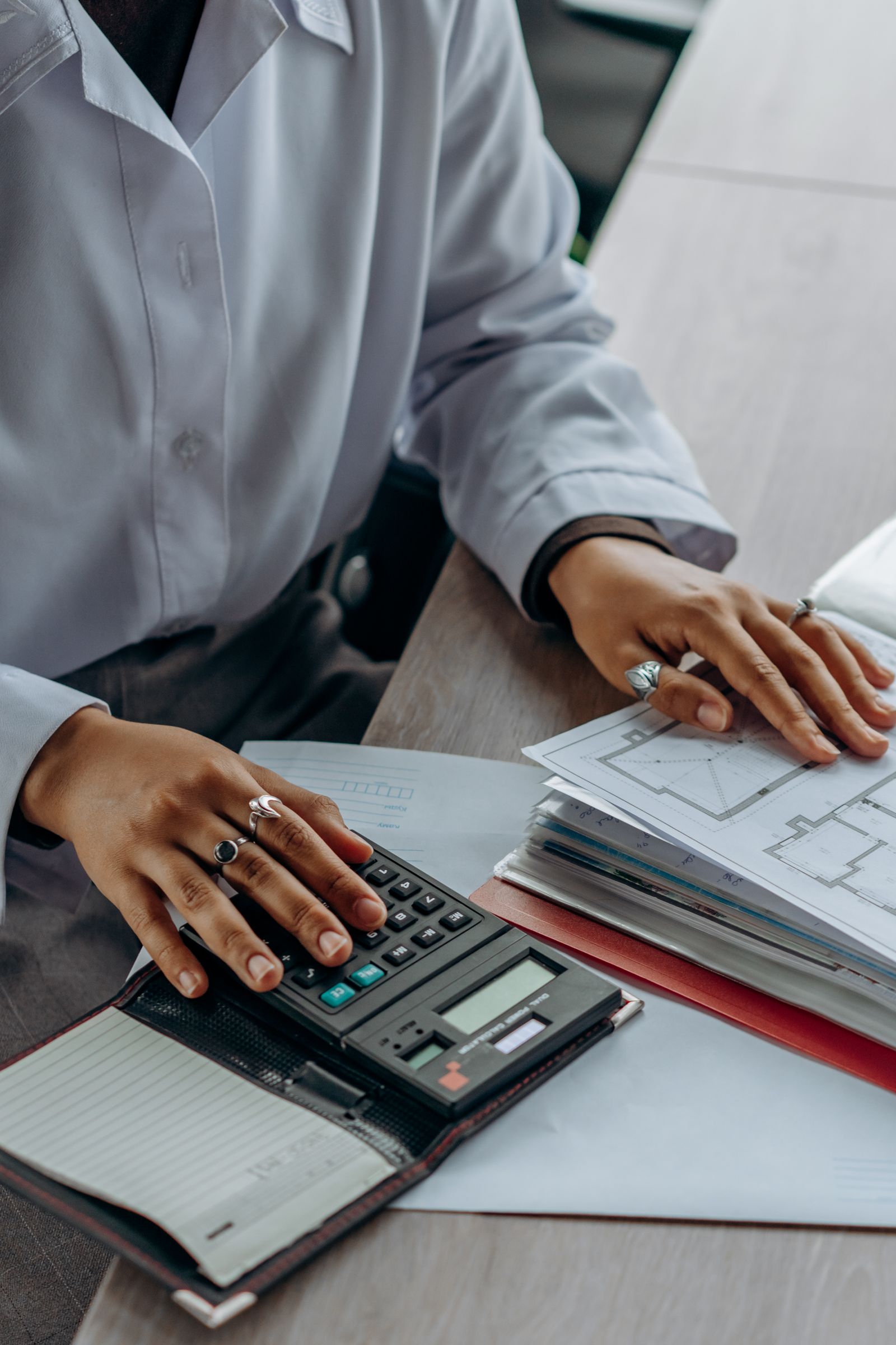 Person working through financial documents with a calculator at a desk
