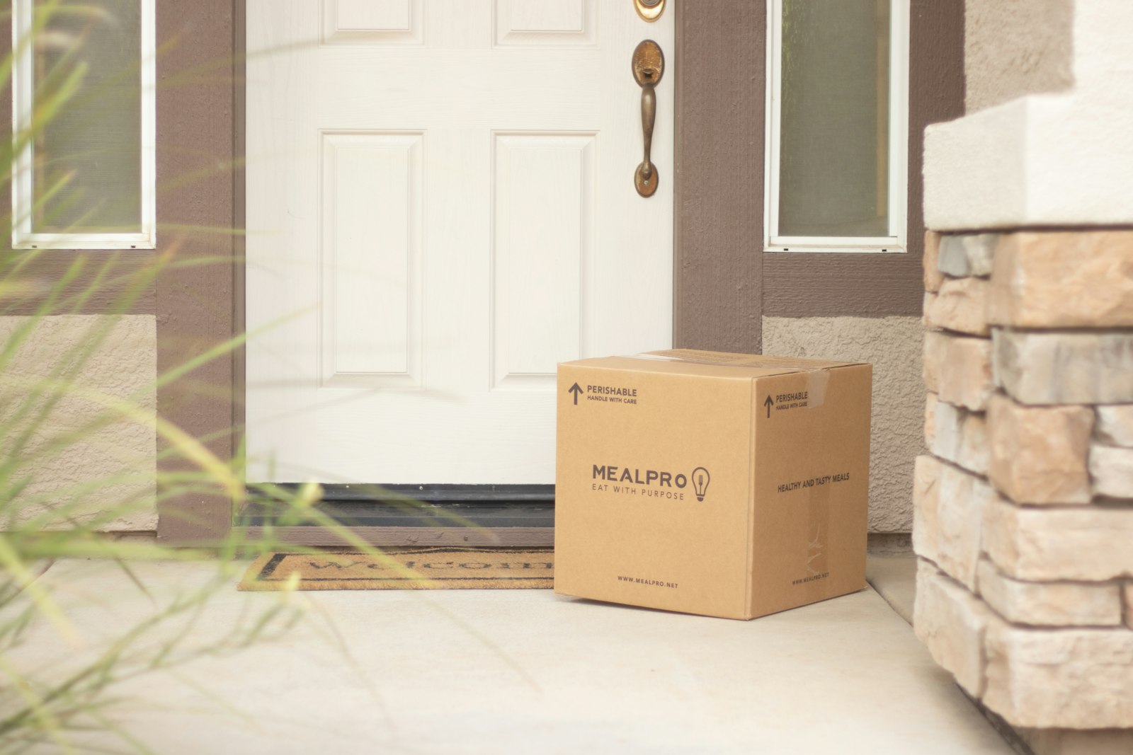 Brown cardboard parcel left beside a white wooden front door
