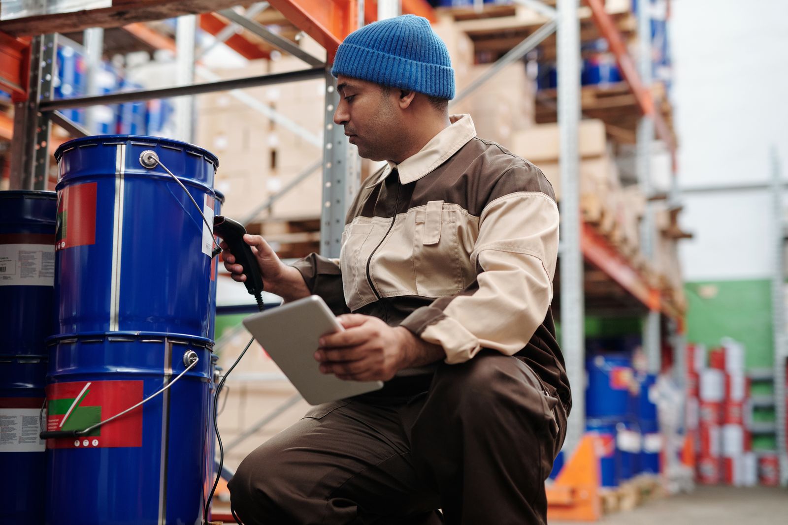 Warehouse employee scanning stock with a handheld scanner and tablet in an industrial storage area