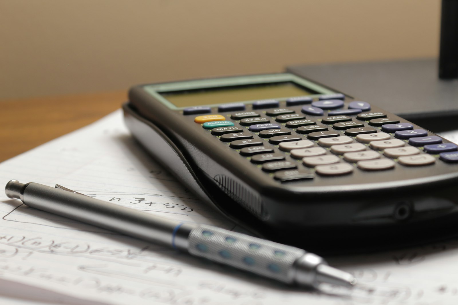A calculator and a pen resting on a sheet of paper