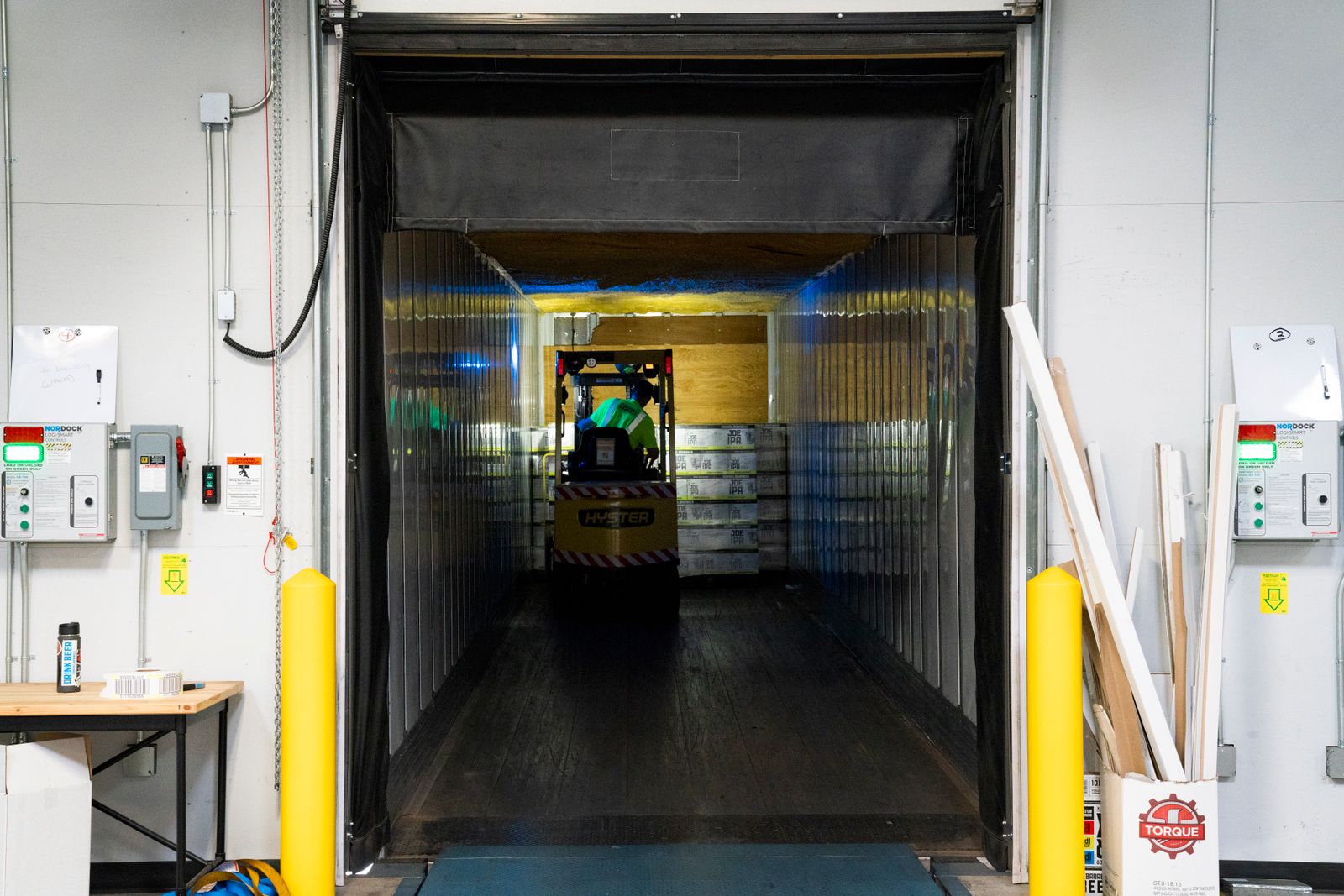 A forklift unloading goods at an industrial loading dock inside a warehouse