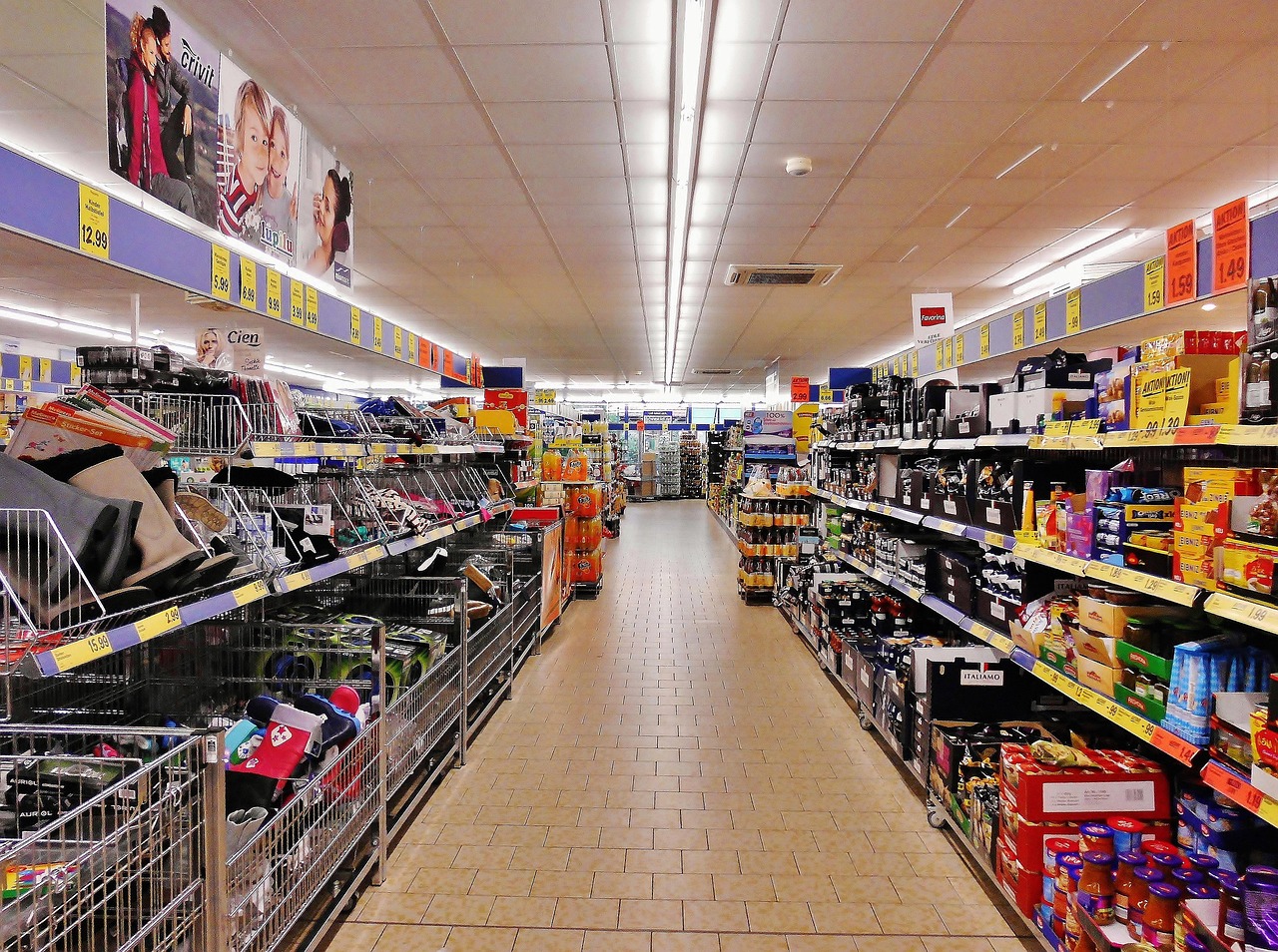 Supermarket aisle with fully stocked shelves and price labels on both sides